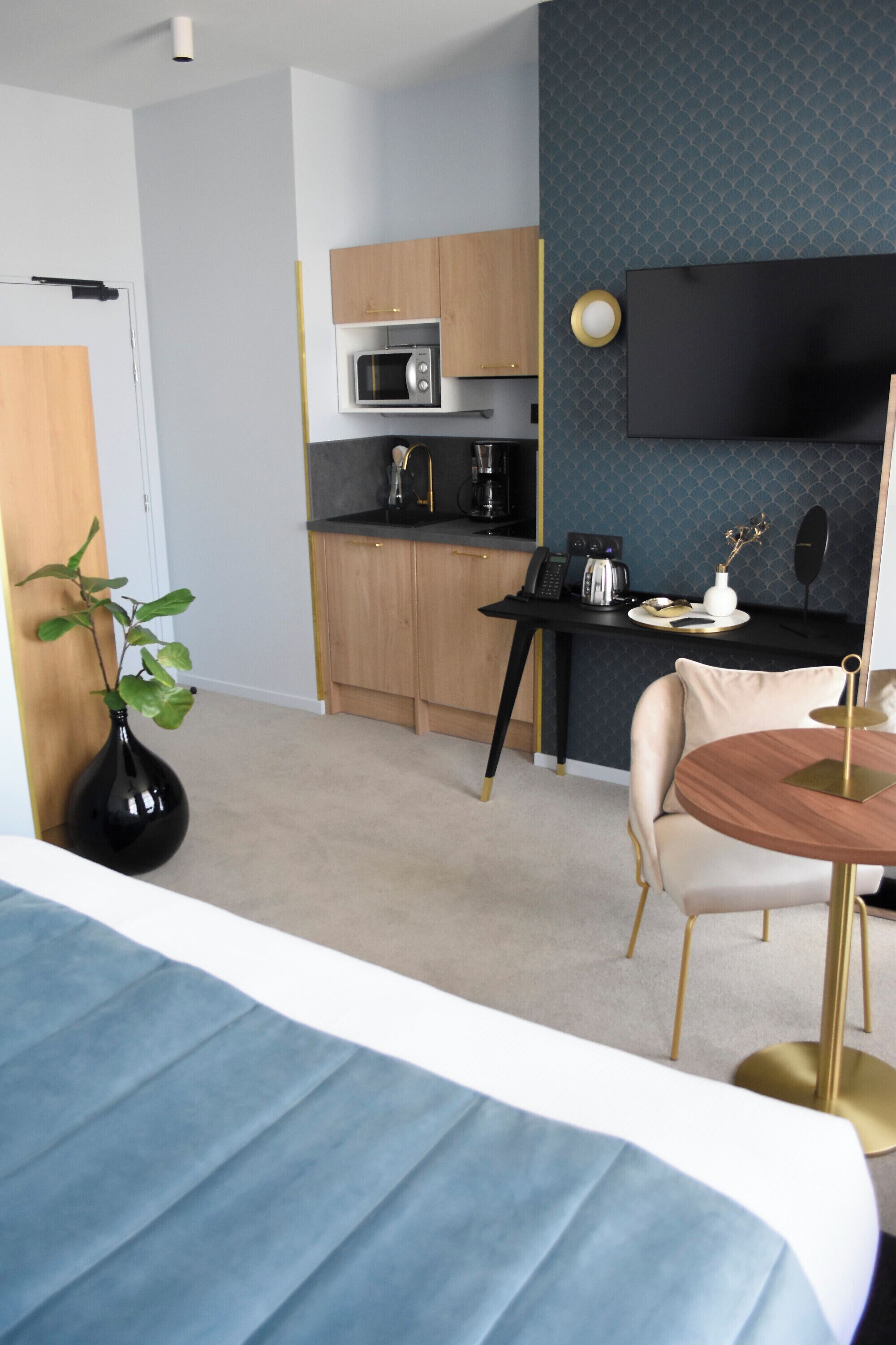 Una habitación de hotel moderna con cama, escritorio, microondas y cafetera.