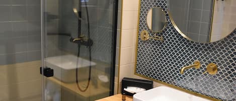 A modern bathroom with a glass-enclosed shower, a white sink, and a mirror with a decorative tile backsplash.