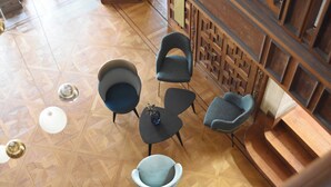 A modern interior with a geometric patterned floor, a bar area with a wooden lattice partition, and several contemporary chairs. - Domitys - Château de la Pilule (Saint-Quentin)