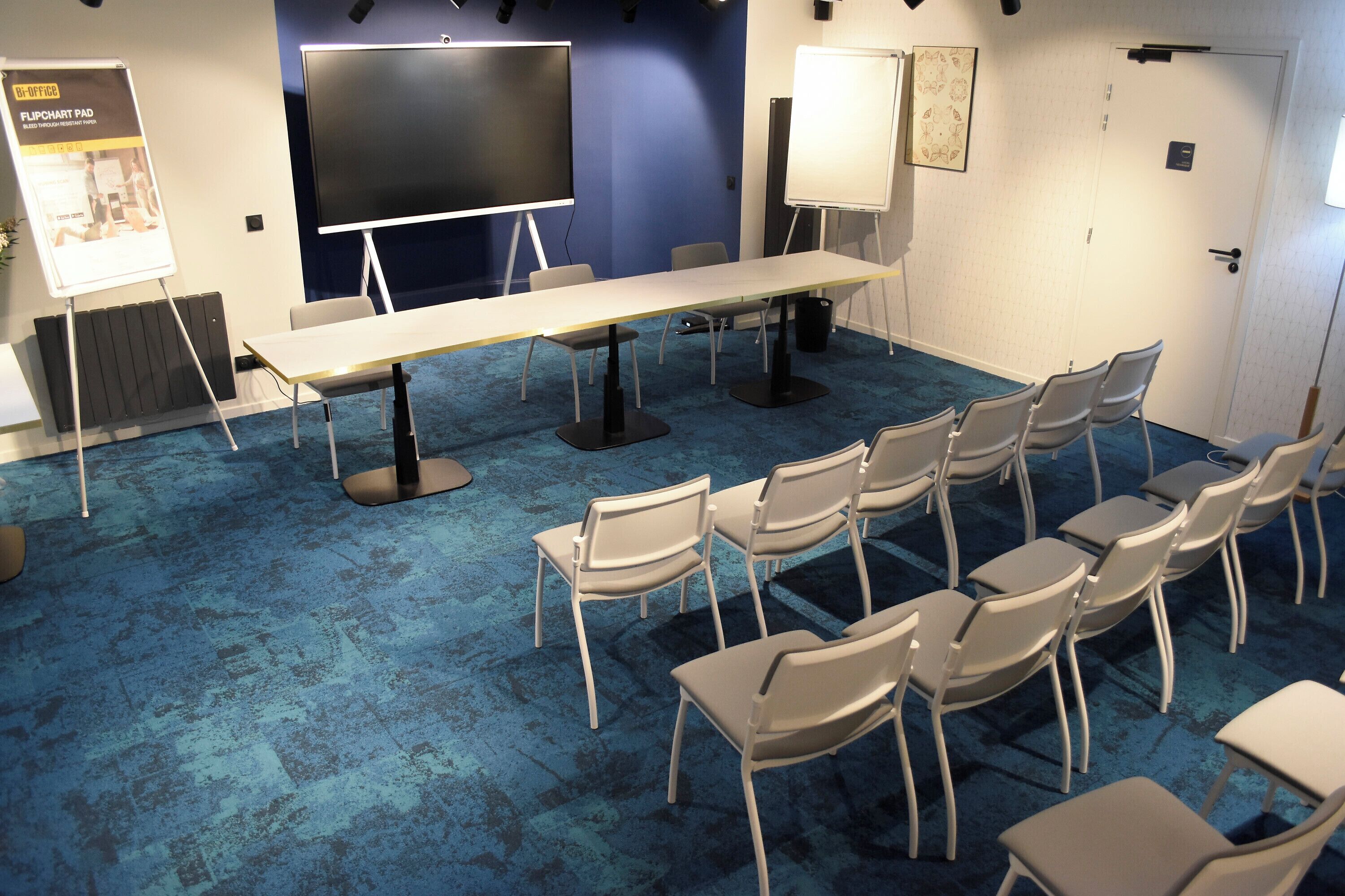 Un salón de conferencias con una gran mesa, sillas, un rotafolio y una pizarra.