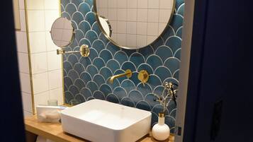A modern bathroom with a white sink, two mirrors, and a blue tiled wall.
