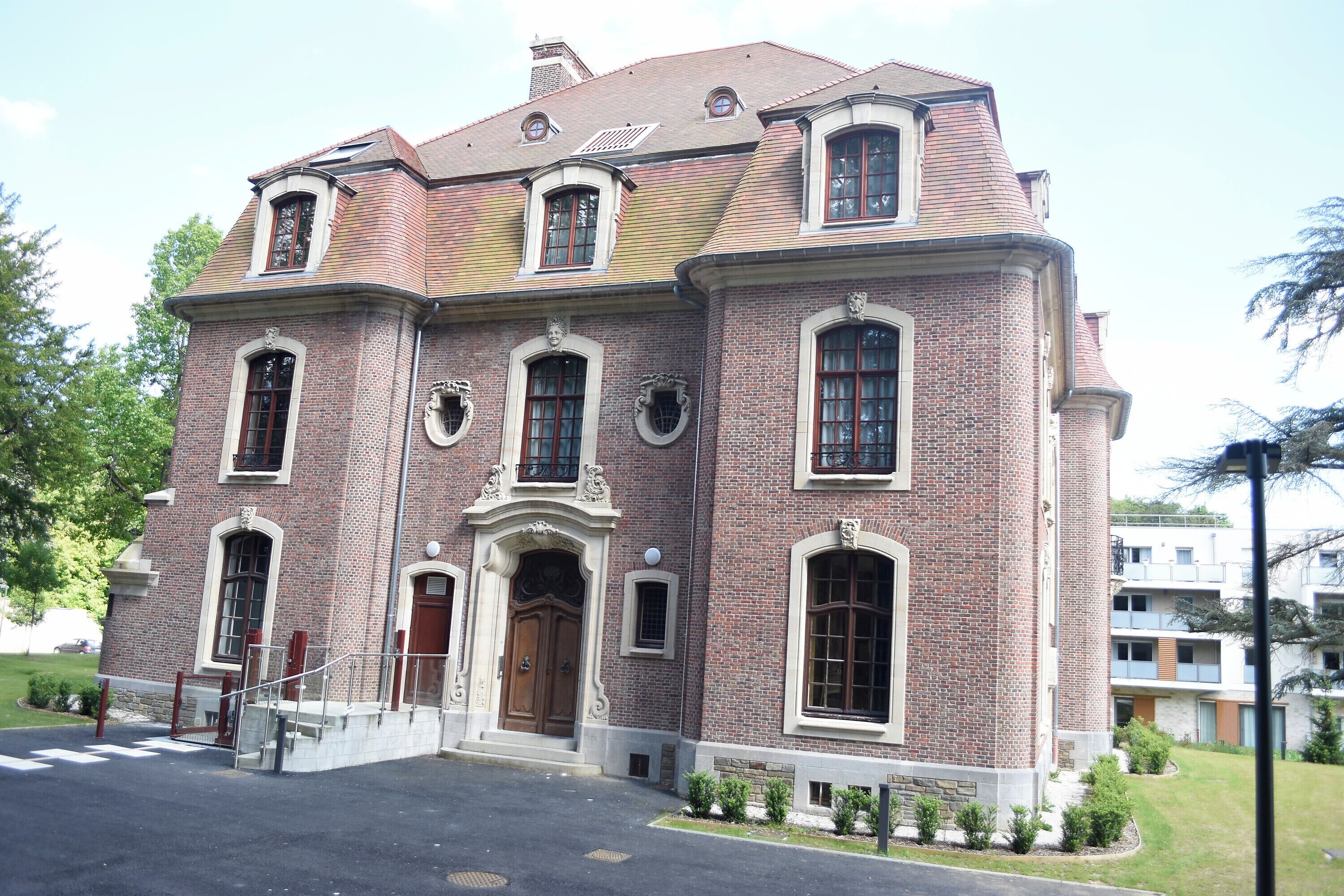 Een groot, historisch bakstenen gebouw met een centrale ingang, meerdere ramen en een symmetrische gevel.