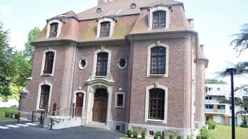 Een groot, historisch bakstenen gebouw met een centrale ingang, meerdere ramen en een symmetrische gevel.