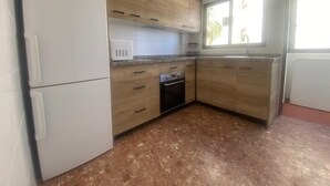 Een keuken met houten kastjes, een ingebouwde oven en een magnetron.