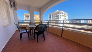 Een balkon met tegels, een tafel en vier stoelen.