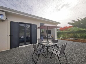 Enjoy a meal or relax in the shaded patio area with a table for four, surrounded by a beautiful garden.