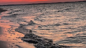 A beach with waves at sunset.