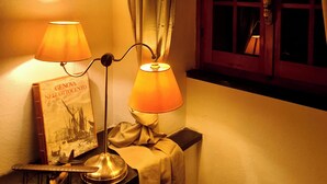 Un coin de pièce avec une fenêtre, une lampe et un livre posé sur une petite table.