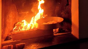 Une cheminée avec un feu crépitant, une bougie et une petite lanterne posées sur le manteau de la cheminée.