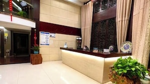 A hotel reception area with a reception desk, a bulletin board, and a potted plant. - Leinuobinguna (Yueqing)