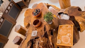 A wooden coffee table with a rustic design, featuring a bowl of decorative stones, a small potted plant, and a tray with glassware. - Leinuobinguna (Yueqing)