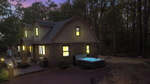 A two-story stone house with a hot tub and outdoor seating area.