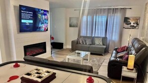 Un salon équipé d’un téléviseur, d’un canapé et d’une table de billard.