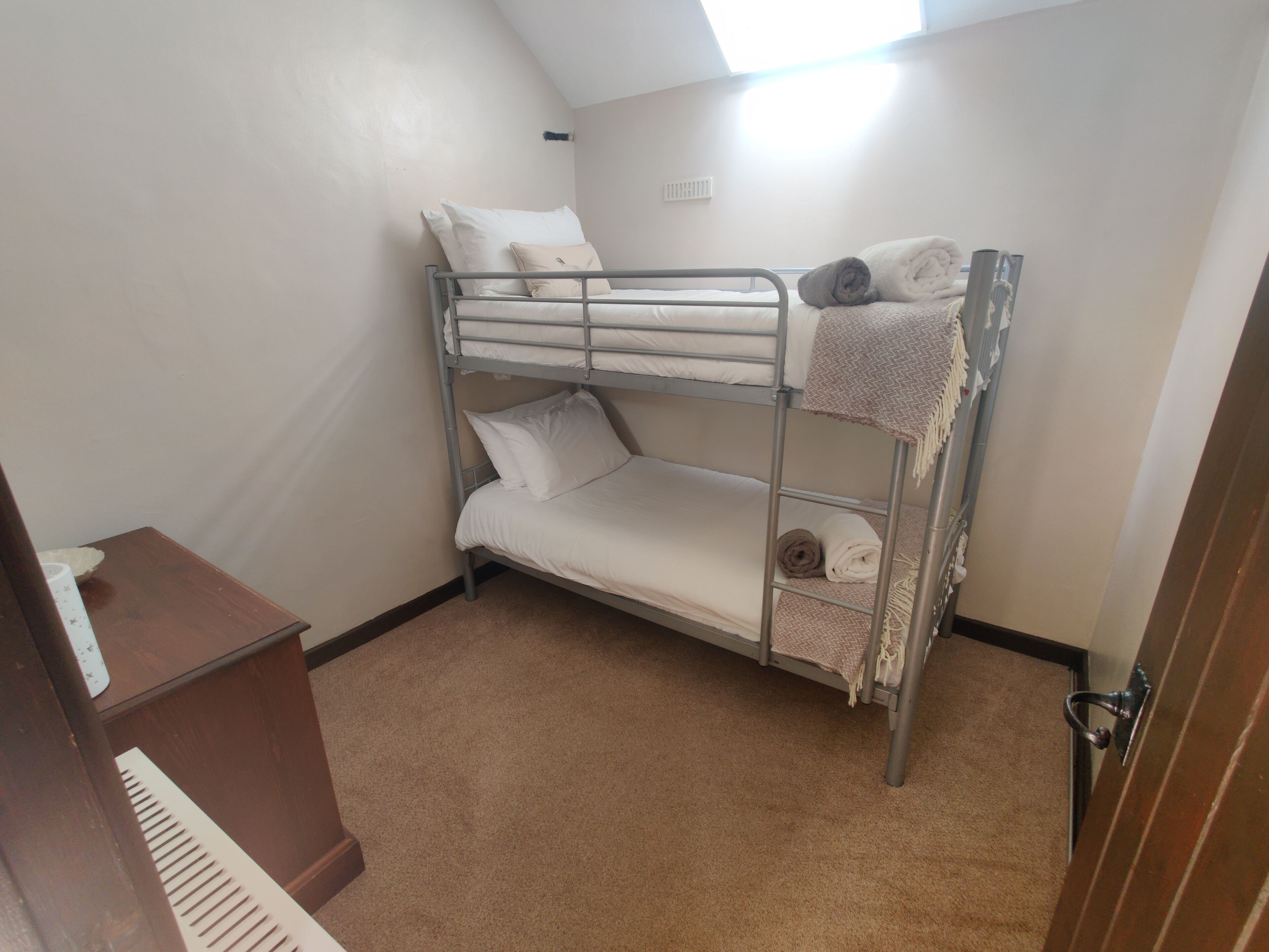 A bunk bed room with a small wooden desk and a radiator.