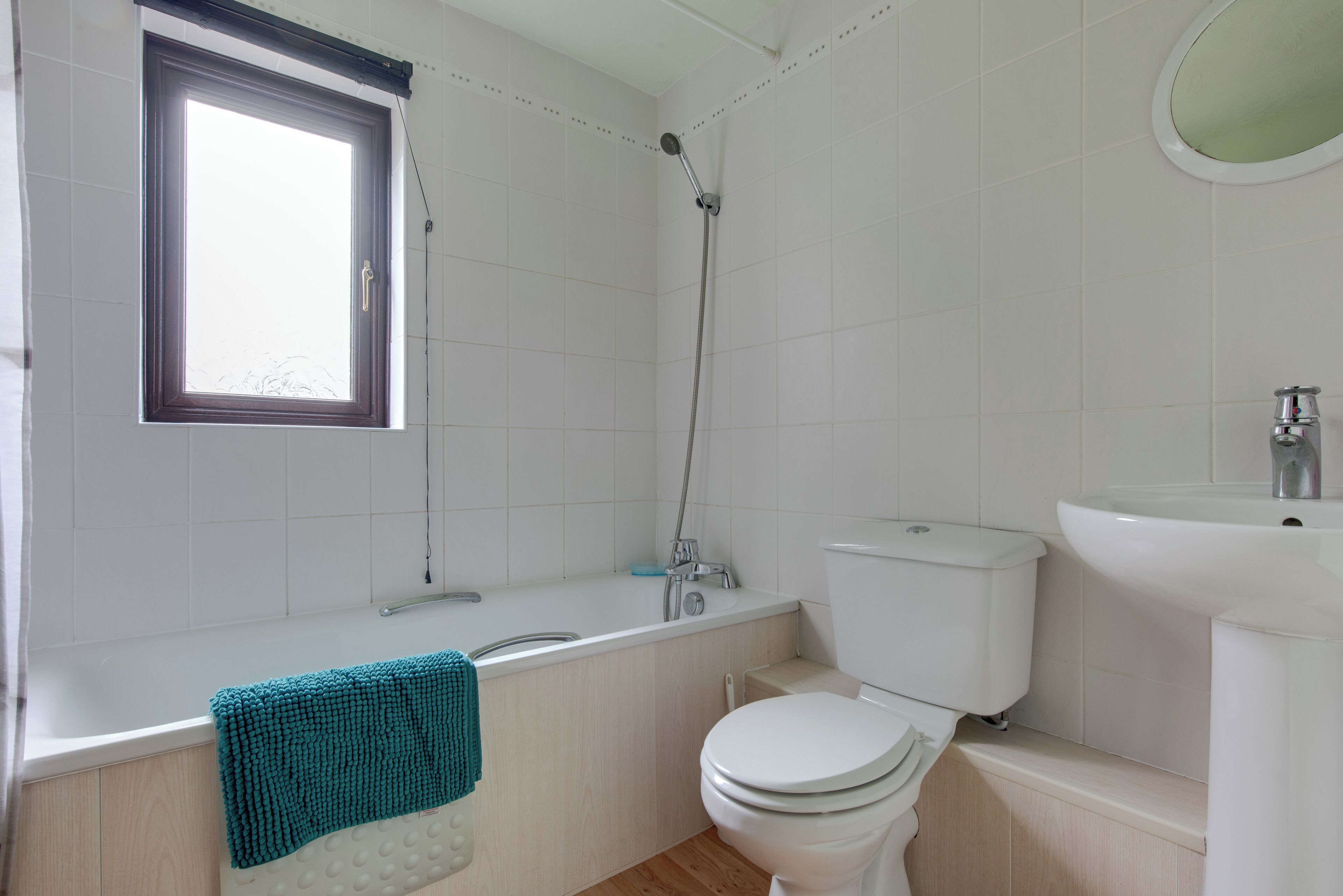 A bathroom with a bathtub, toilet, sink, and a window.