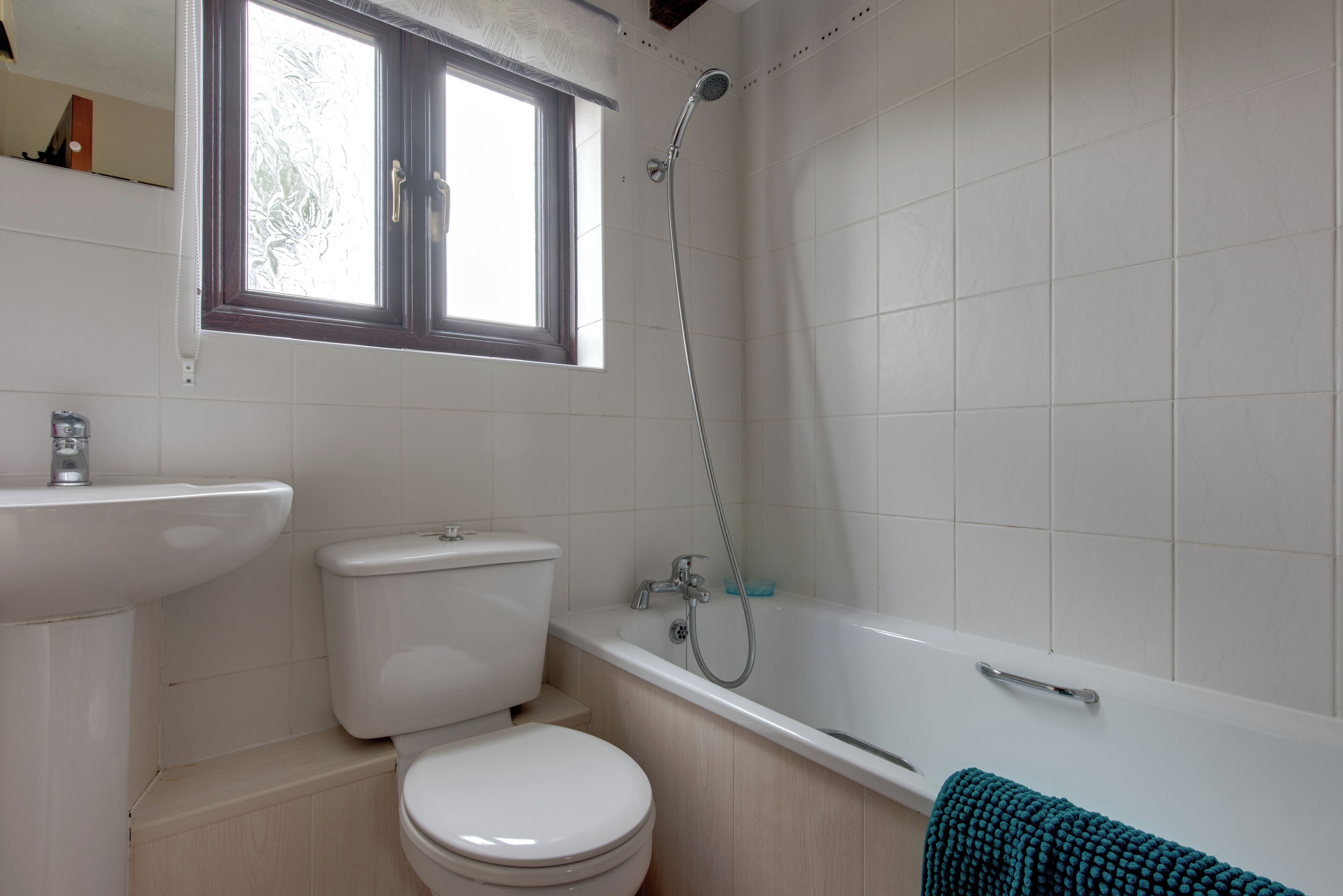 A bathroom with a toilet, sink, bathtub, and a window.