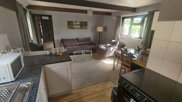 A compact kitchen with a microwave, stove, and dining area.