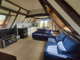 Un espacio habitable estilo loft con cocina, un sofá grande azul y un televisor.