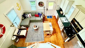 Un espace de vie compact comprenant un canapé, une table basse et un coin repas. On peut également apercevoir un ventilateur de plafond et une cuisinière.