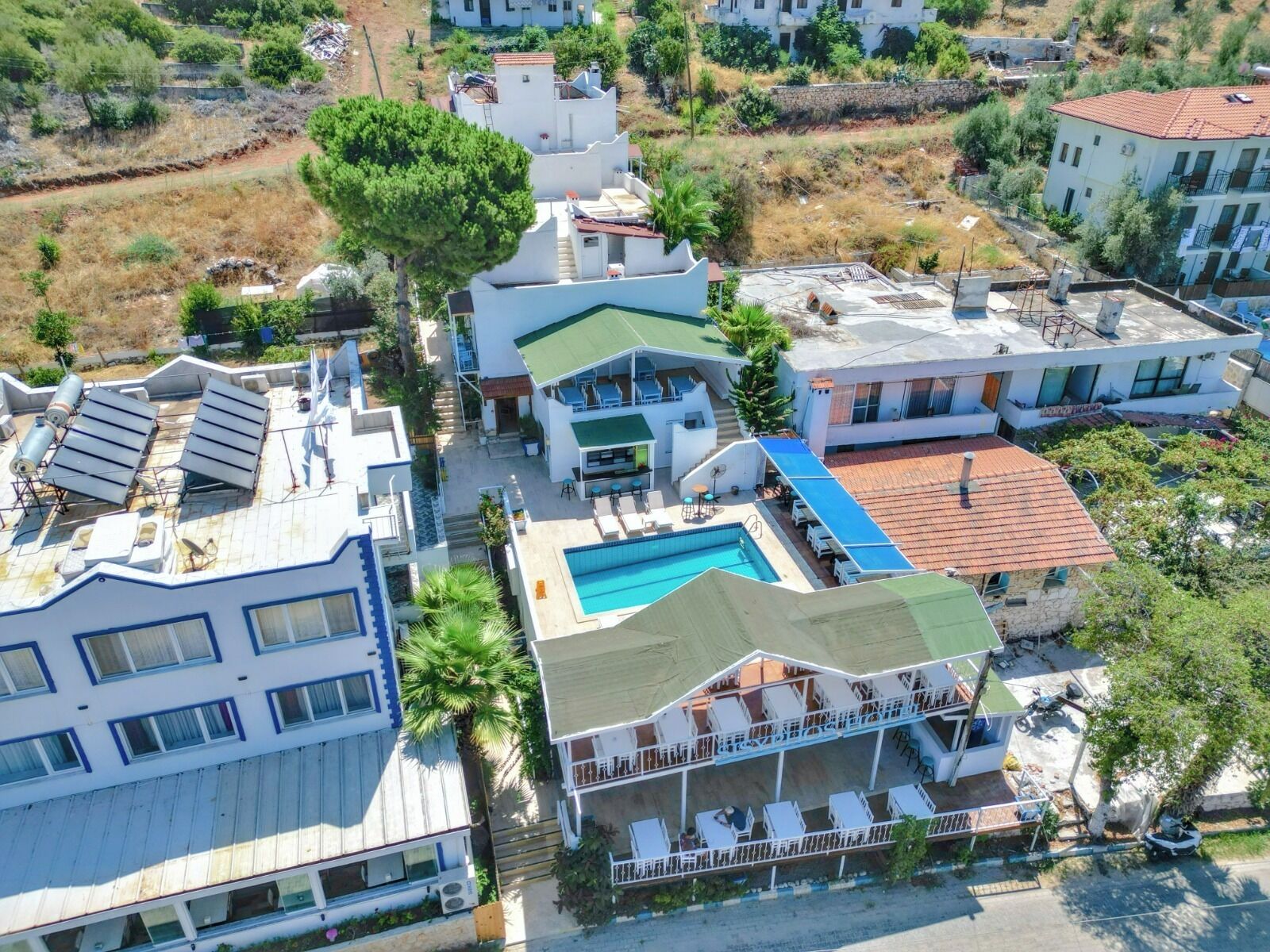 Un quartier résidentiel comprenant plusieurs immeubles, dont une maison avec une piscine et un balcon doté d’un espace salon extérieur.