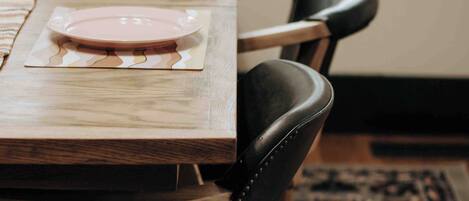 A wooden dining table with two pink plates and black leather chairs.
