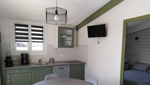 A compact kitchen with a dining area, a built-in dishwasher, and a flat-screen TV mounted on the wall. - Le Figuier, Gite Rural du Seuil, Near La Rochelle (Villedoux)