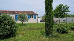 A house with a tiled roof, a fenced yard, and a small tree in the foreground. - Le Figuier, Gite Rural du Seuil, Near La Rochelle (Villedoux)