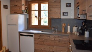 A kitchen with wooden cabinets, a refrigerator, a sink, and a window with a view of trees. - Balcony, fireplace or stove, tv, 88m², Pralognan-la-Vanoise (Pralognan-la-Vanoise)