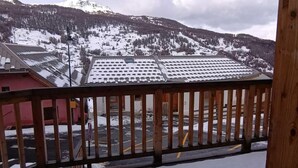 Eine verschneite Berglandschaft mit Blick auf ein Gebäude mit flachem Dach und ein rotes Gebäude im Vordergrund.