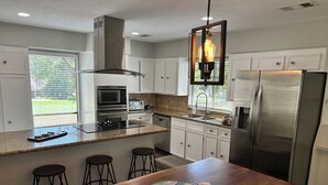 A modern kitchen with a central island, stainless steel appliances, and a large window.