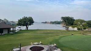 A golf course with a water body in the background, a pavilion, and a well-maintained lawn.