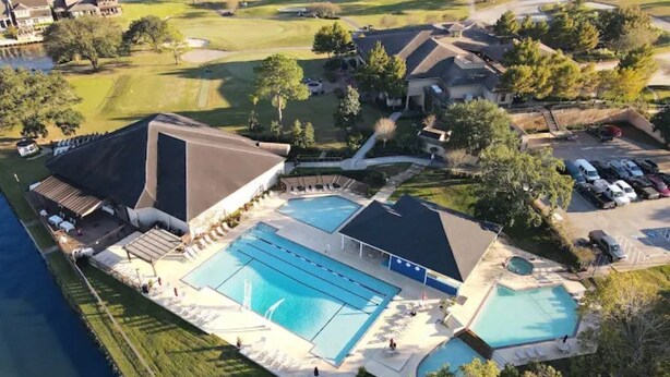 An aerial view of a resort with multiple swimming pools, a golf course, and residential buildings.