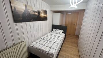 Un dormitorio con cama, un radiador, un cuadro y una puerta.
