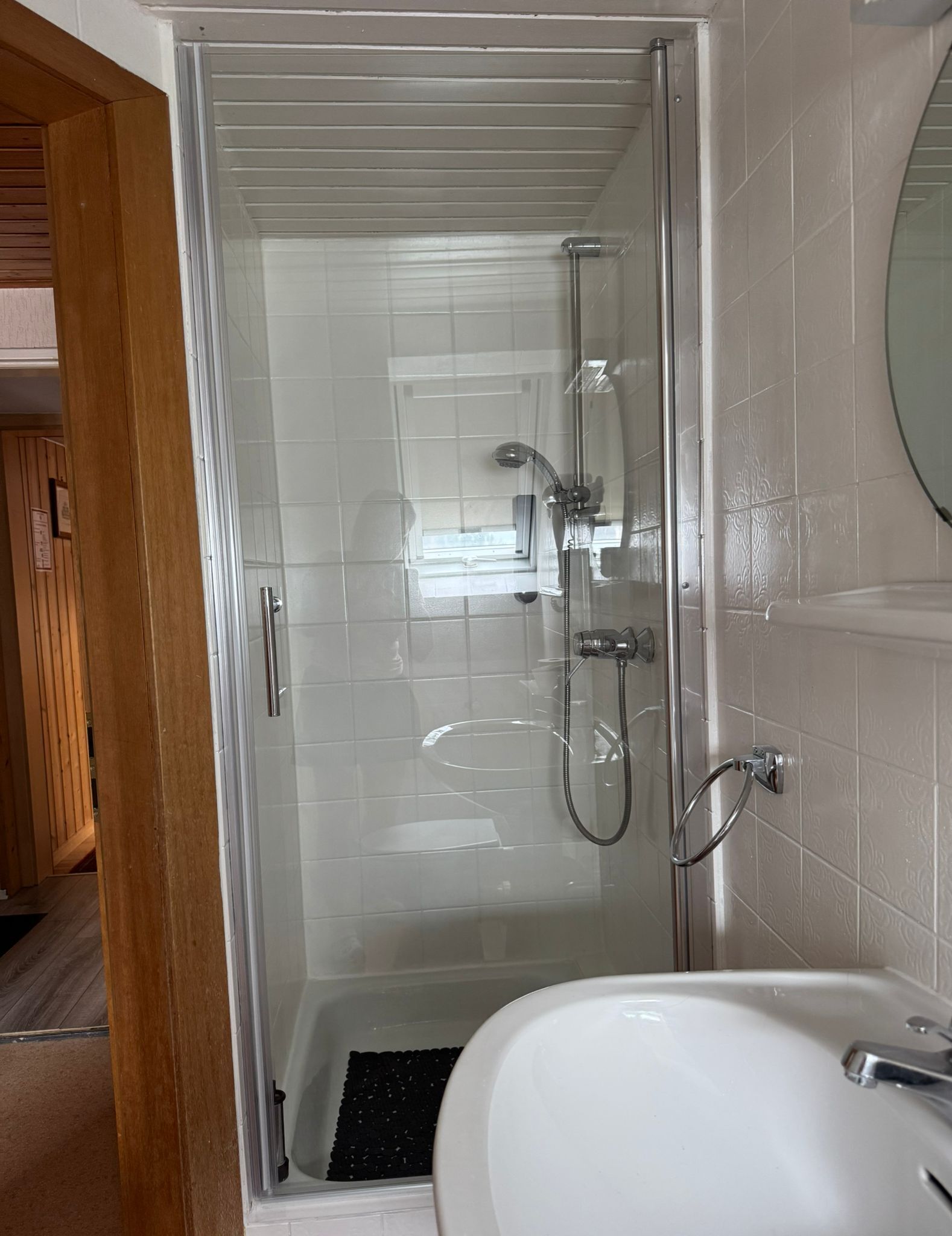 A shower enclosure with a glass door, a handheld showerhead, and a wall-mounted faucet.