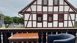 A traditional half-timbered house with a balcony, a wooden table, and a blue chair. - Gasthaus Nangfa Engel  (Edermünde)