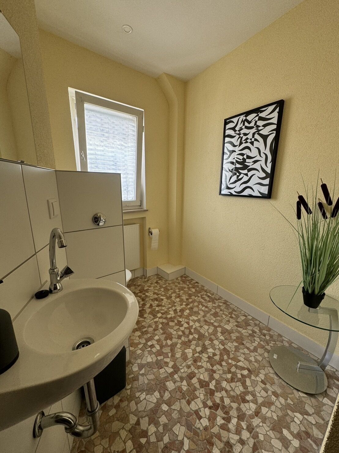 Une salle de bain avec un lavabo, un miroir et une fenêtre.