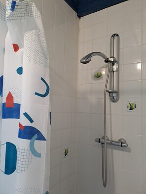 Chuveiro, toalhas de banho, sabonete, papel higiênico