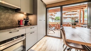 Une cuisine moderne dotée d’un four encastré et d’un coin repas avec une table et des chaises en bois.