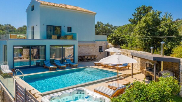 A modern two-story house with a swimming pool, outdoor seating, and a stone wall.