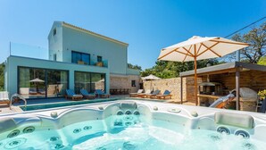 A modern villa with a swimming pool, a hot tub, and outdoor seating.