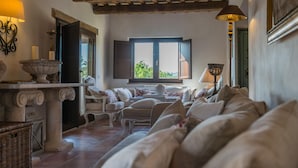 A cozy living room with a sofa set, a stone table with candles, and a view through a window.