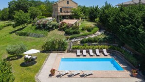 A house with a swimming pool, surrounded by lush greenery and a stone staircase leading to a deck.