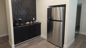Uma cozinha moderna com geladeira de aço inoxidável, armários escuros e painel de fundo trabalhado.