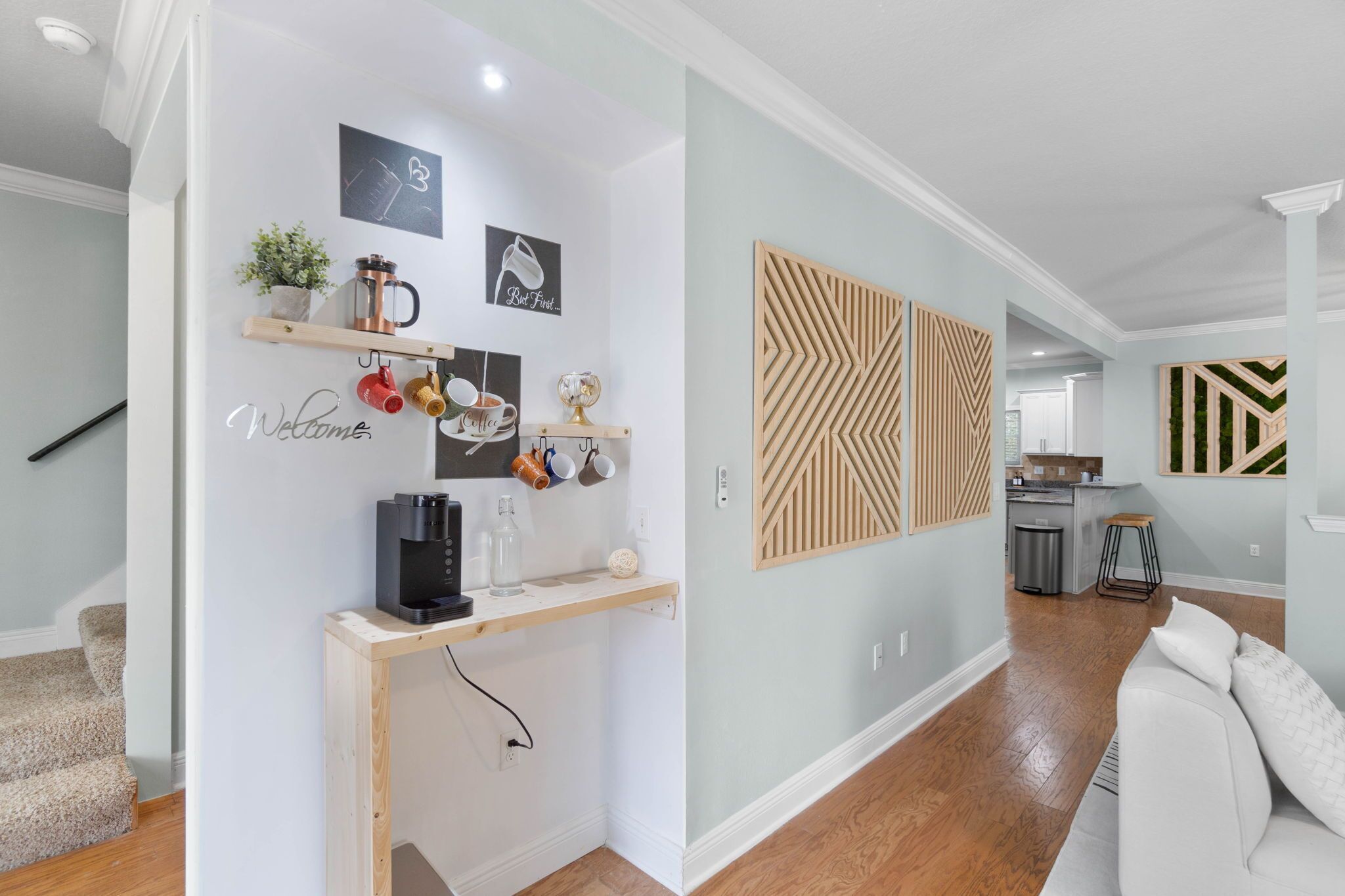 A modern kitchen with a central island, a coffee machine, and a hanging shelf with mugs.