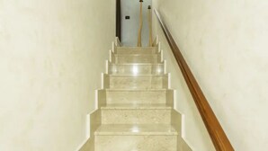 Una scala in marmo con corrimano in legno che porta a una porta in cima.