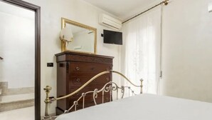 Una camera da letto con un letto, una cassettiera, uno specchio e un televisore.