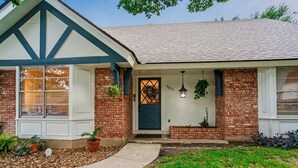 A house with a gabled roof, a front door with a wreath, and potted plants. - The TX Oasis.  Boho Paradise.  Huge Backyard. (San Antonio)