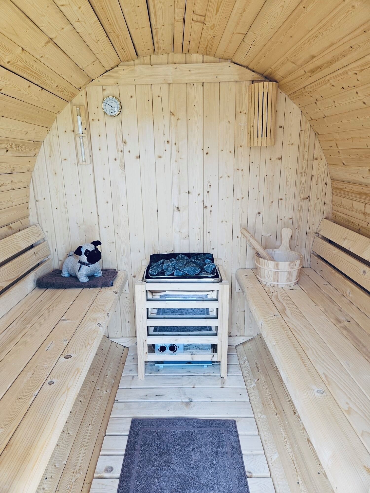 Un sauna avec des murs et des bancs en bois, un radiateur et un petit panier pour chien.