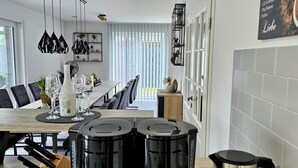 Une cuisine moderne avec un coin repas, comprenant un espace dédié au café avec plusieurs machines à café et une bouilloire.
