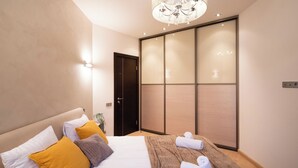 Una camera d'albergo moderna con un letto grande, un armadio scorrevole e un lampadario.